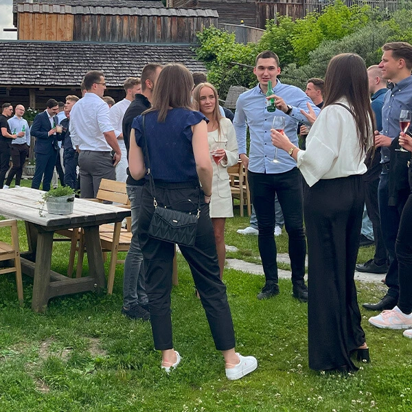 Mitarbeitende aus verschiedenen Ländern im Austausch bei einer informellen Outdoor-Veranstaltung – kulturelle Begegnung in entspannter Atmosphäre.