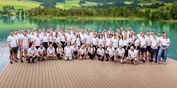 Großes Team von OMS Retail bei einer gemeinsamen Veranstaltung am See – Symbol für gelebte Unternehmenskultur und länderübergreifende Zusammenarbeit.