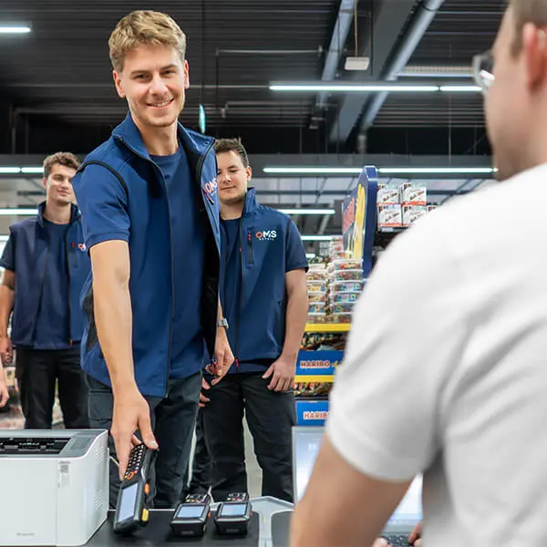 OMS-Retail-Mitarbeiter übergibt im Laden einen Scanner – Symbolbild für Inventurdifferenzen.