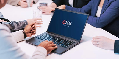 Besprechung am Konferenztisch mit geöffnetem Laptop – Fokus auf Zusammenarbeit und digitale Prozesse bei OMS Retail.