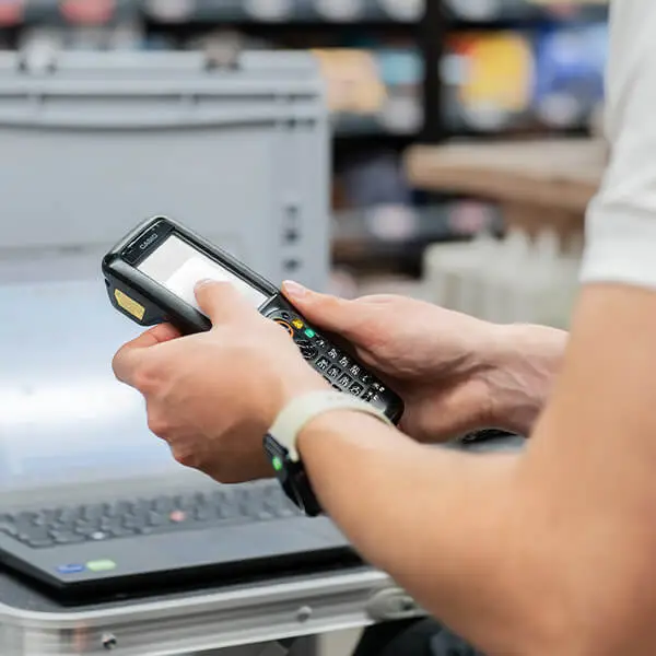 Mitarbeiter scannt Waren mit Handscanner neben Laptop für Bestandesaufnahme