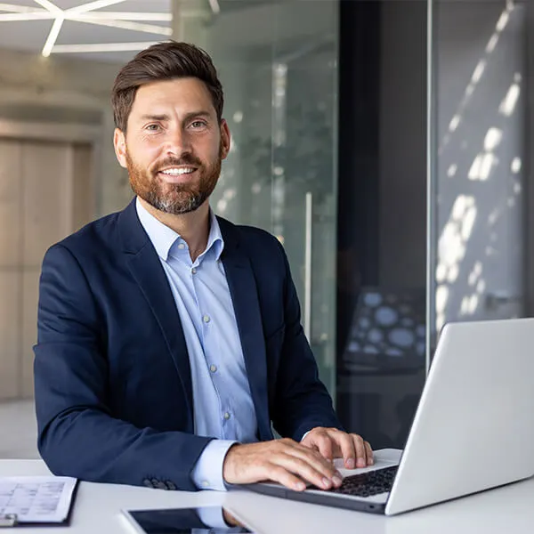 Ein Geschäftsmann sitzt am Schreibtisch und arbeitet am Laptop – Symbolbild für die Frage: Was ist ein Inventar?