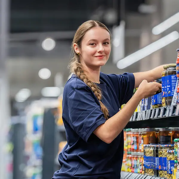 Mitarbeiterin von OMS Retail ordnet Produkte im Supermarktregal während einer Bestandesaufnahme